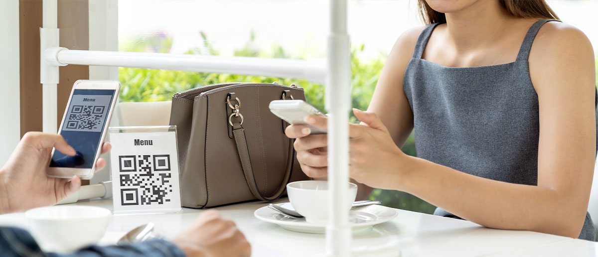 Pareja en cafetería escaneando código QR con el móvil